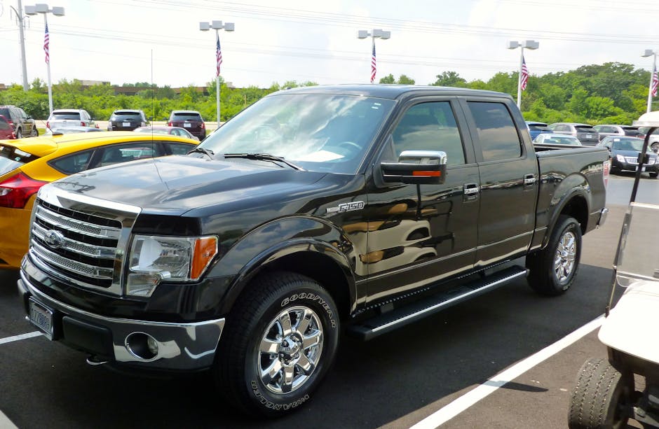 Black Ford F-150 pickup truck displayed at an outdoor dealership lot on a sunny day