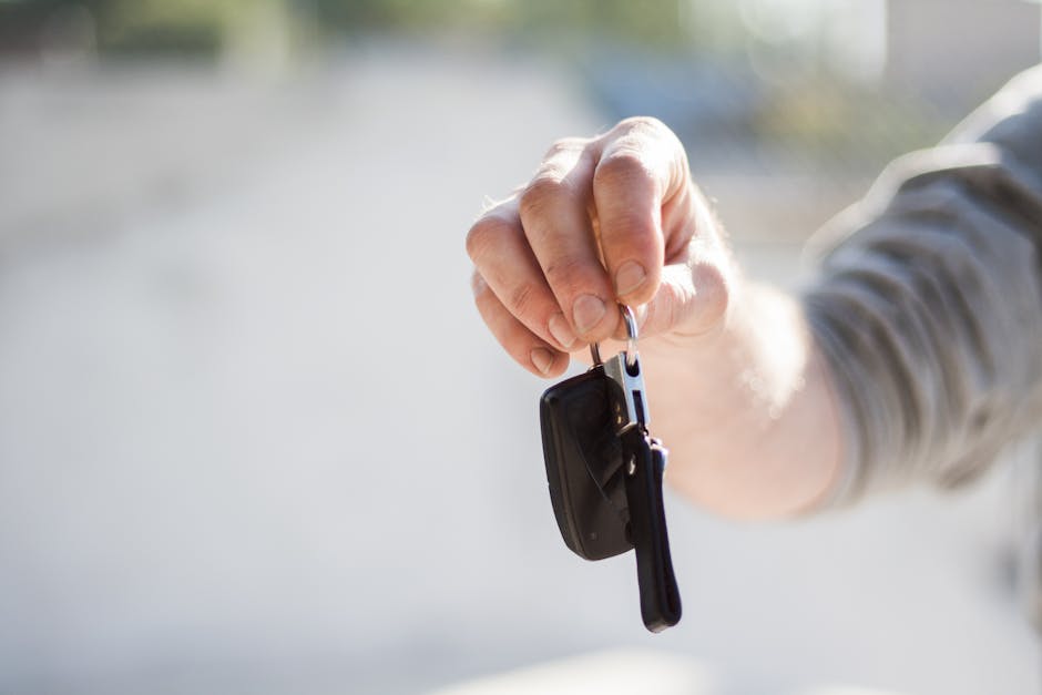 Close-up of a hand handing over car keys, signifying purchase or rental